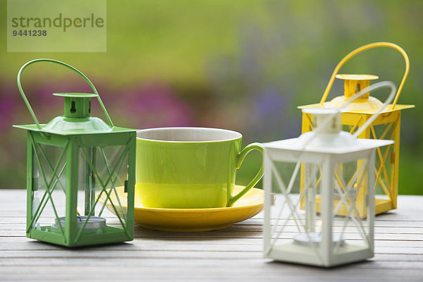 Gartentisch mit Kaffeetassen und Windlicht