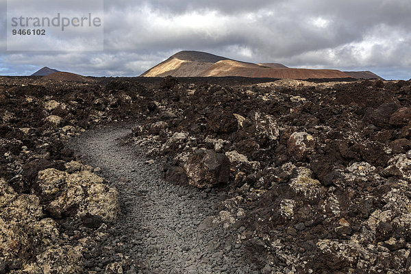 Weg durch ein Lavafeld  Vulkanlandschaft  Feuerberge  Vulkane  hinten Caldera Blanca  Lanzarote  Kanarische Inseln  Spanien  Europa