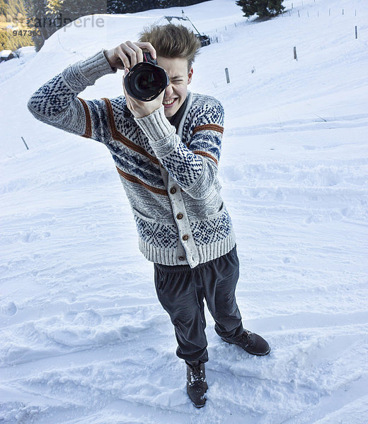Junger Mann im Schnee fotografiert mit digitaler Spiegelreflexkamera  Hochbrixen  Brixen im Thale  Tirol  Österreich  Europa