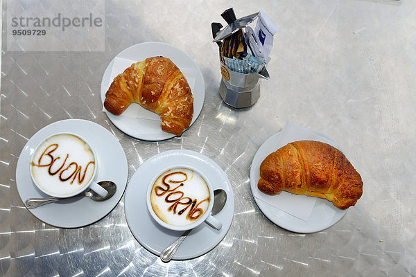 Zwei Tassen Cappuccino  mit Schrift Buon Giorno auf dem Milchschaum  zwei Croissants  Sardinien  Italien  Europa