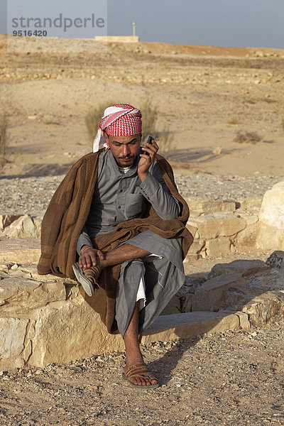 Jordanier in traditioneller Kleidung telefoniert mit Mobiltelefon  Wüstenschloss Qusair 'Amra oder Qusaie Amra  Jordanien  Asien