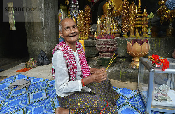 Ältere kambodschanische Frau  Novizin mit Räucherstäbchen vor Buddhafigur  Angkor Wat Tempelkomplex  Siam Reap  Kambodscha  Asien