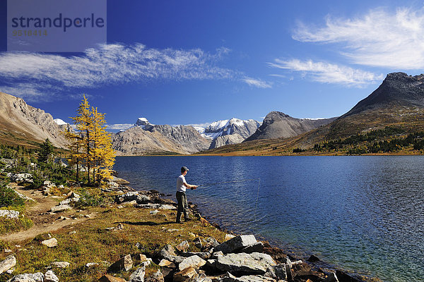 Ein Fischer steht am Ufer des Ptarmigan Lake und angelt  Rocky Mountains  Banff-Nationalpark  Alberta  Kanada  Nordamerika