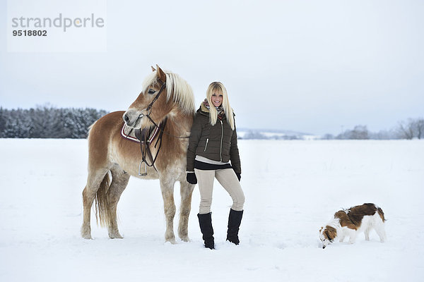 Junge Frau mit einem Haflinger im Schnee