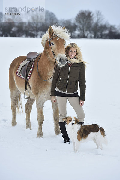 Junge Frau mit einem Haflinger im Schnee