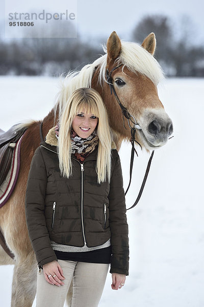 Junge Frau mit einem Haflinger im Schnee