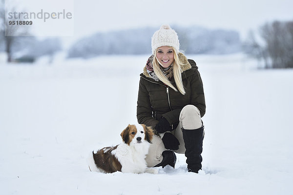 Junge Frau mit einem Kooikerhondje-Hund im Schnee