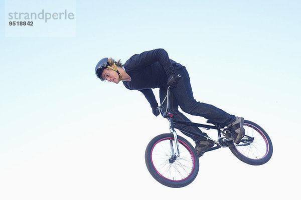 Teenager auf einem BMX-Rad springt in die Luft