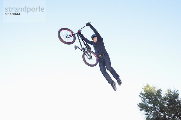 Teenager auf einem BMX-Rad springt in die Luft