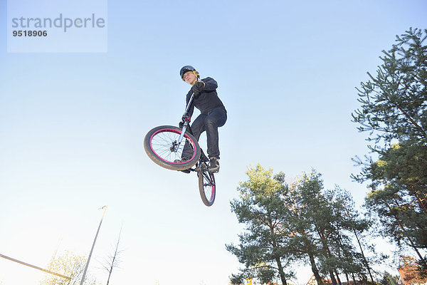 Teenager auf einem BMX-Rad springt in die Luft