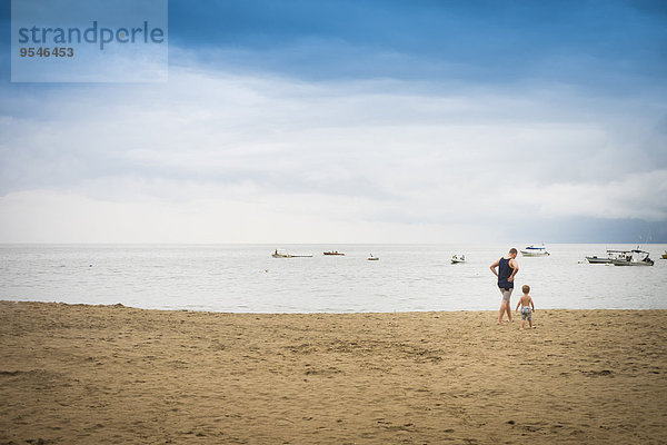 Mexiko  Mann mit Kleinkind  der am Strand spazieren geht.
