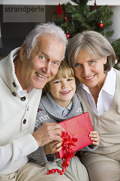 Glücklicher kleiner Junge erhält Weihnachtsgeschenk von seinen Großeltern