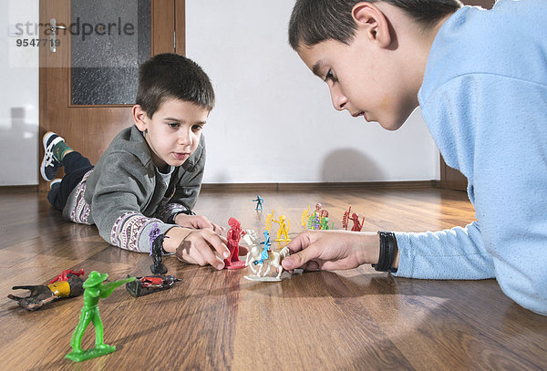Zwei Jungen  die zu Hause mit Miniaturfiguren auf dem Boden spielen