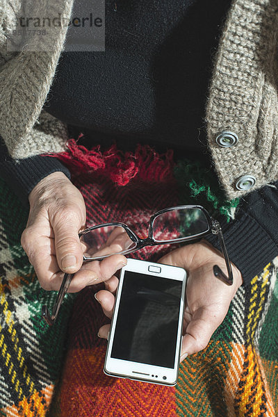 Seniorin mit Brille und Smartphone  Teilansicht