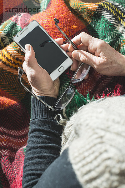 Seniorin mit Brille und Smartphone  Teilansicht