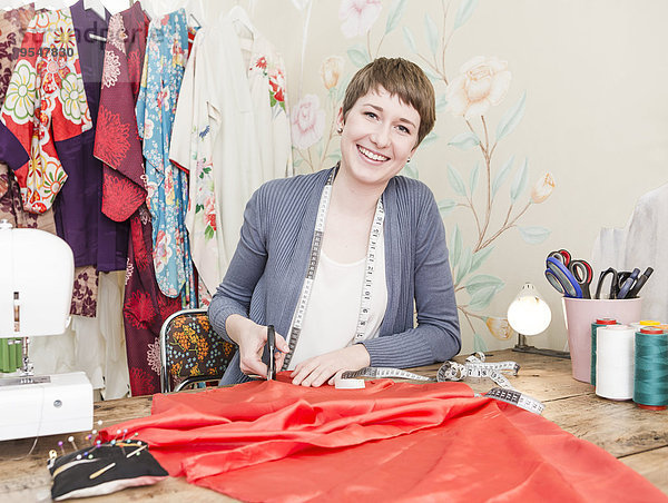 Porträt einer lächelnden Modedesignerin am Schreibtisch