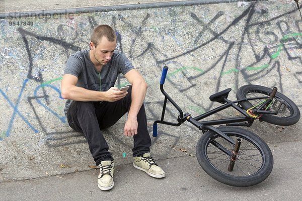 Junger Mann mit BMX-Bike über sein Smartphone