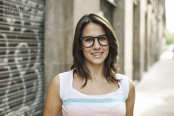 Porträt einer lächelnden jungen Frau mit schwarzer Brille