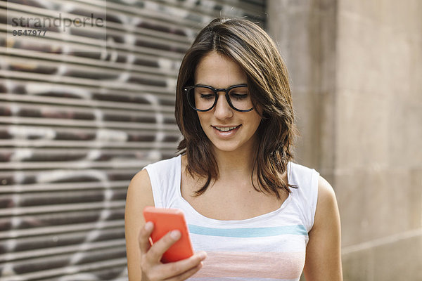 Lächelnde junge Frau mit Smartphone Lesung SMS