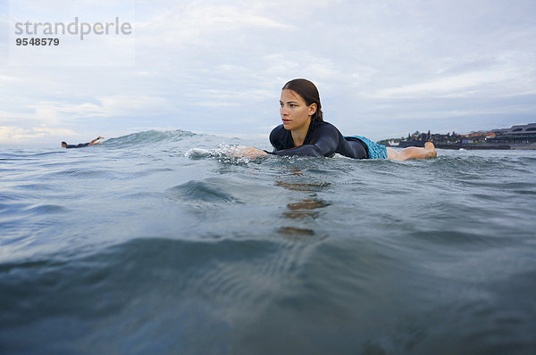 Indonesien  Bali  Canggu  junge Frau auf dem Surfbrett liegend  auf dem Weg nach vorn