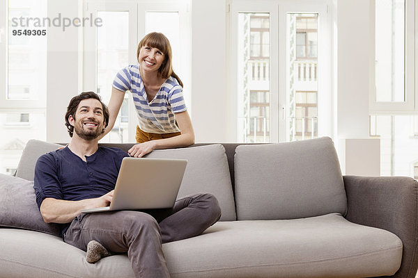 Lächelndes Paar mit Laptop zu Hause