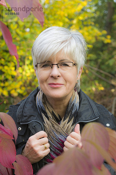 Porträt einer lächelnden Seniorin mit kurzen grauen Haaren und Brille