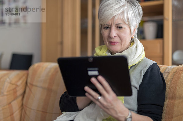 Seniorin mit digitalem Tablett auf dem Sofa