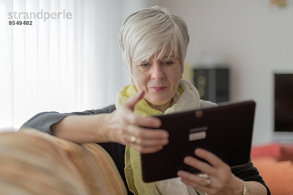 Seniorin mit digitalem Tablett auf dem Sofa