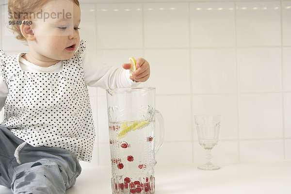 Kleines Mädchen nimmt Zitronenscheiben aus der Wasserkaraffe