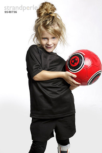 Porträt eines blonden Mädchens mit rotem Fußball in Fußballsportbekleidung vor weißem Hintergrund
