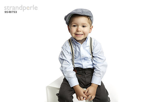 Porträt des grinsenden kleinen Jungen mit Mütze und Hosenträgern