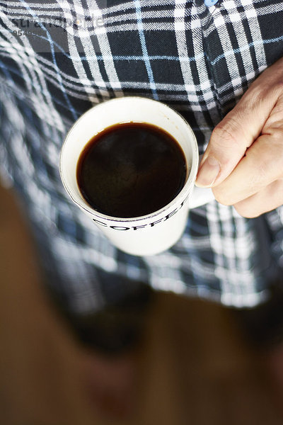Mann im Pyjama mit Tasse Kaffee  Teilansicht