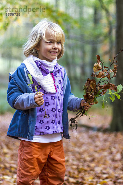 Porträt eines kleinen Mädchens mit Herbstlaub und Pflanzen