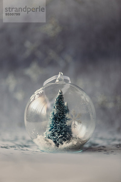 Weihnachtskugel aus Glas mit Tannenbaum und Kunstschnee im Innern