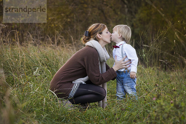 Mutter küsst Sohn auf der Wiese