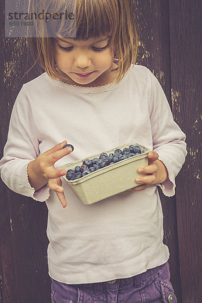 Kleines Mädchen mit einer Schachtel Heidelbeeren
