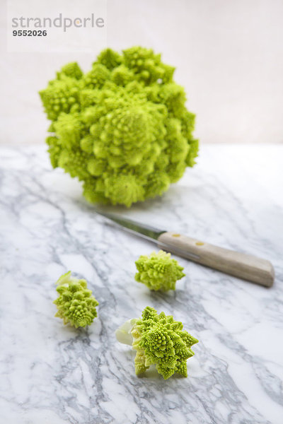 Romanesco  Brassica oleracea convar. botrytis var. botrytis  und Küchenmesser auf weißem Marmor