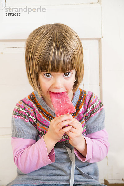 Porträt eines kleinen Mädchens beim Essen von Himbeereis-Lolly