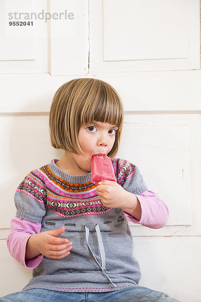 Porträt eines kleinen Mädchens beim Essen von Himbeereis-Lolly