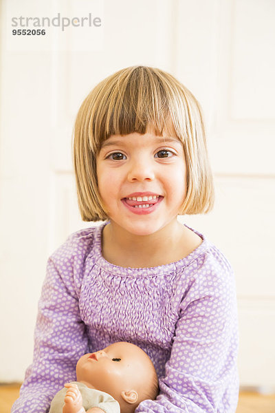 Porträt eines lächelnden Mädchens mit Puppe