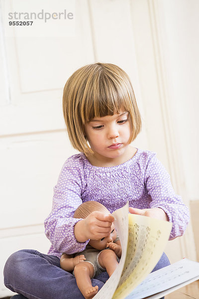 Porträt eines kleinen Mädchens beim Blättern in einem Liederbuch