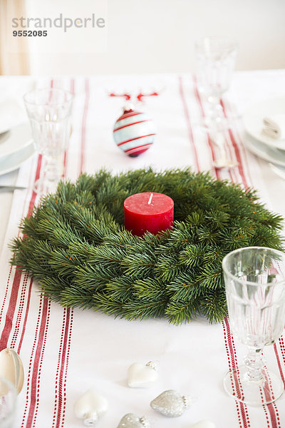 Rot-weiß gedeckter Tisch mit Adventskranz zur Weihnachtszeit