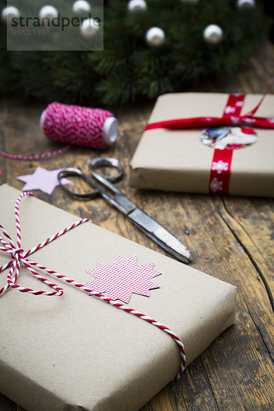 Verpackte Weihnachtsgeschenke und Scheren auf dunklem Holz