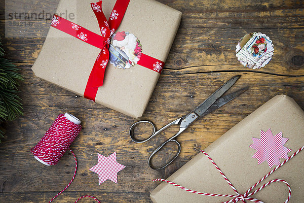 Verpackte Weihnachtsgeschenke und Scheren auf dunklem Holz