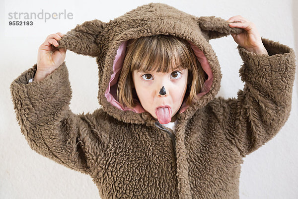 Portrait eines kleinen Mädchens  das sich als Bär verkleidet und ein Gesicht macht.