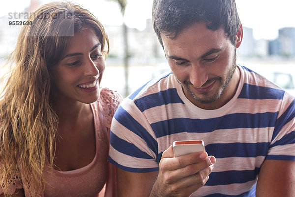 Junges Paar sendet Nachrichten mit einem Smartphone