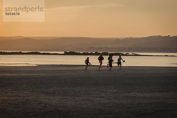 UK  England  Cornwall  Kinder laufen am Strand bei Sonnenuntergang