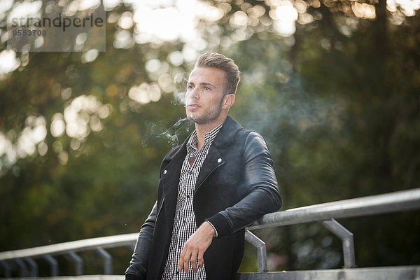 Porträt eines jungen Mannes  der eine Zigarette raucht.