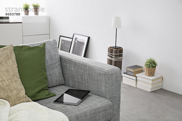 Digitales Tablett auf der Couch liegend in einem modernen Wohnzimmer