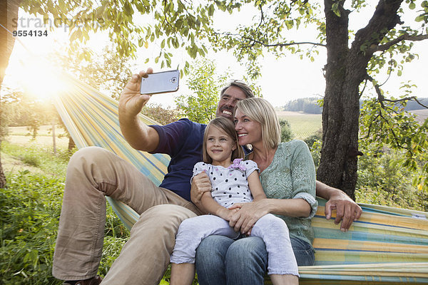 Glückliche Familie  die Selfie in der Hängematte nimmt